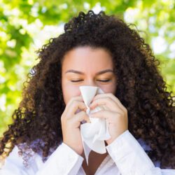 Beautiful woman blowing nose in park